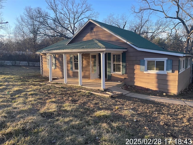 view of front of home with fence, covered porch, and metal roof