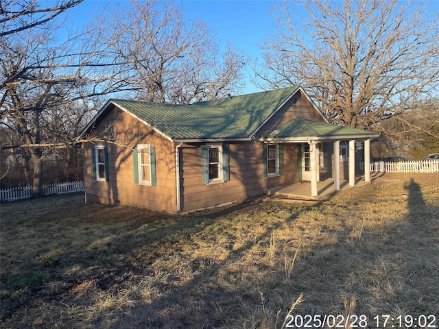 view of side of property featuring a lawn, metal roof, and fence