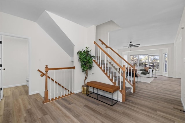 stairway featuring a ceiling fan, wood finished floors, and baseboards