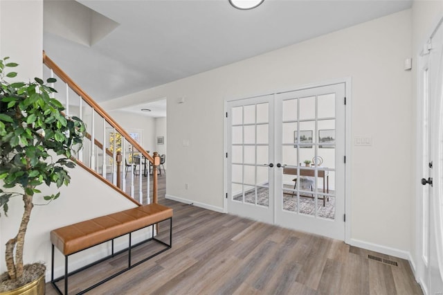 entryway with wood finished floors, visible vents, baseboards, stairs, and french doors