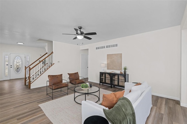 living room with visible vents, stairs, baseboards, and wood finished floors