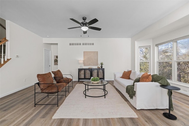 living room featuring visible vents, baseboards, wood finished floors, and stairs