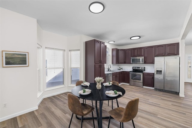 kitchen with a sink, light wood-type flooring, appliances with stainless steel finishes, and light countertops