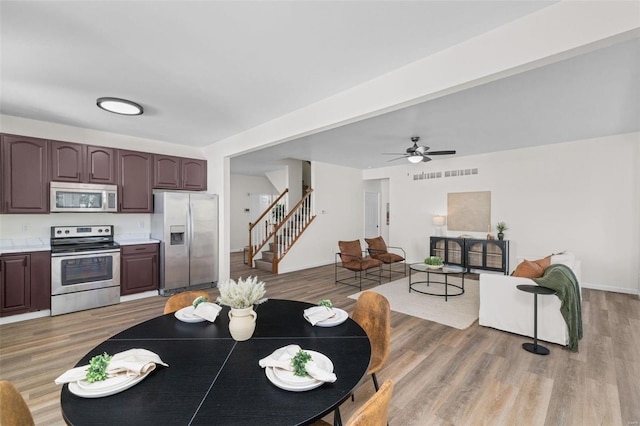 dining room featuring ceiling fan, stairway, visible vents, and light wood-style flooring