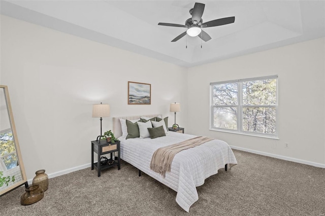 bedroom with a tray ceiling, carpet flooring, baseboards, and ceiling fan