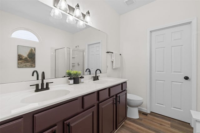 bathroom with a sink, visible vents, wood finished floors, and a shower stall