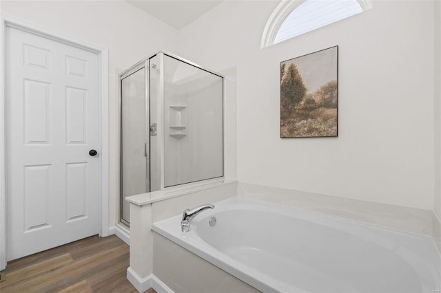 bathroom with wood finished floors, a stall shower, and a bath