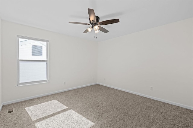 carpeted empty room with visible vents, baseboards, and a ceiling fan