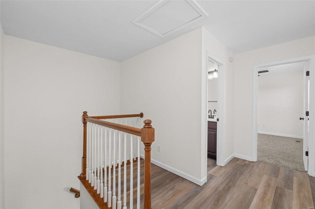 corridor featuring wood finished floors, attic access, an upstairs landing, and baseboards