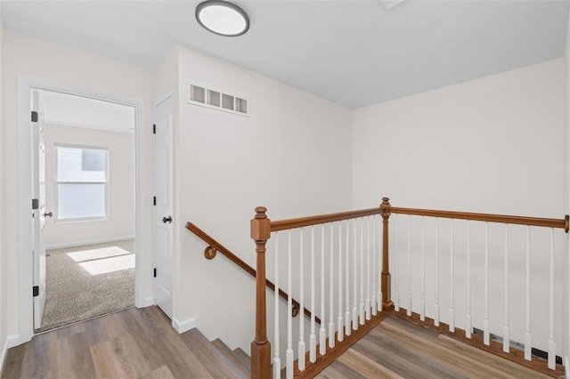 staircase with wood finished floors, visible vents, and baseboards