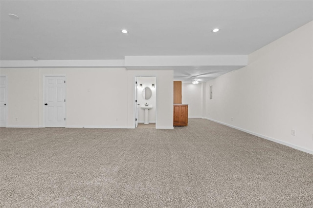 unfurnished living room featuring recessed lighting, baseboards, light carpet, and a sink