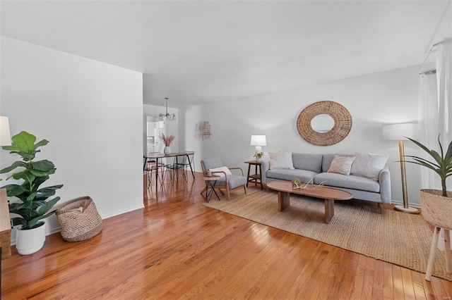 living area with a notable chandelier, light wood-style flooring, and baseboards