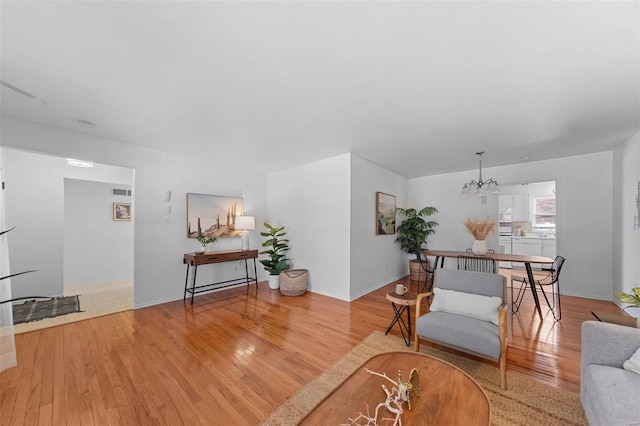 living area with baseboards, an inviting chandelier, and wood finished floors