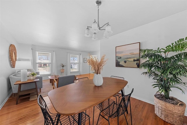 dining area featuring a chandelier, light wood-style flooring, and baseboards