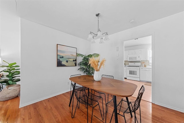 dining room featuring baseboards, a notable chandelier, and light wood-style flooring