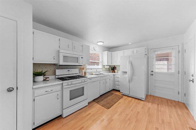 kitchen featuring white appliances, light wood-type flooring, light countertops, and a sink