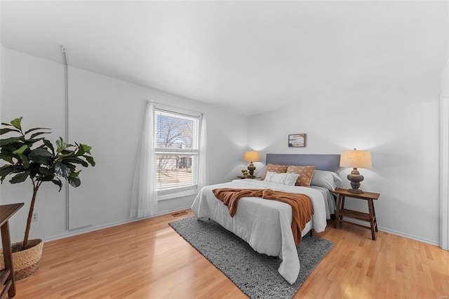 bedroom with visible vents, baseboards, and light wood-type flooring