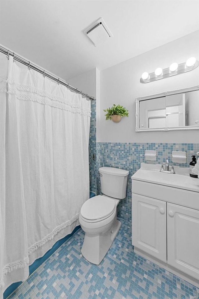 full bathroom featuring tile patterned floors, visible vents, toilet, tile walls, and vanity