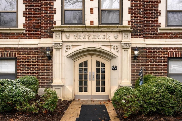 view of exterior entry featuring french doors and brick siding