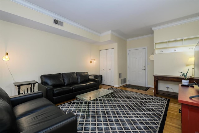 living area with visible vents, baseboards, wood finished floors, and ornamental molding