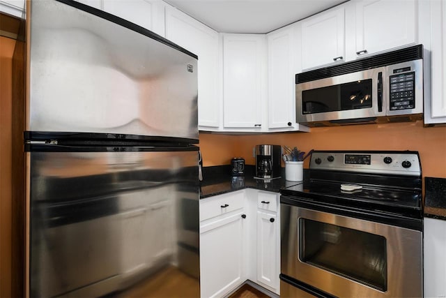 kitchen featuring dark stone countertops, appliances with stainless steel finishes, and white cabinetry