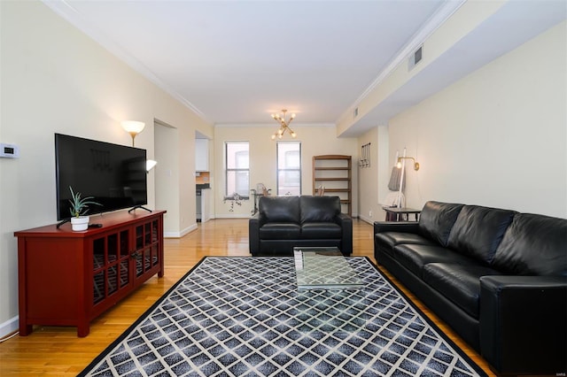 living room with visible vents, ornamental molding, an inviting chandelier, light wood finished floors, and baseboards