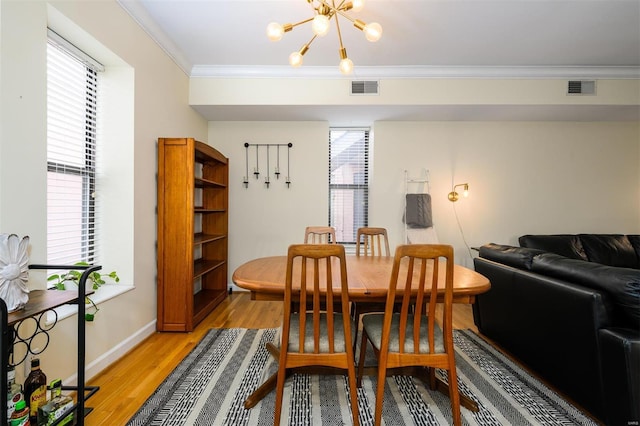 dining area featuring visible vents, light wood-style floors, a chandelier, and crown molding