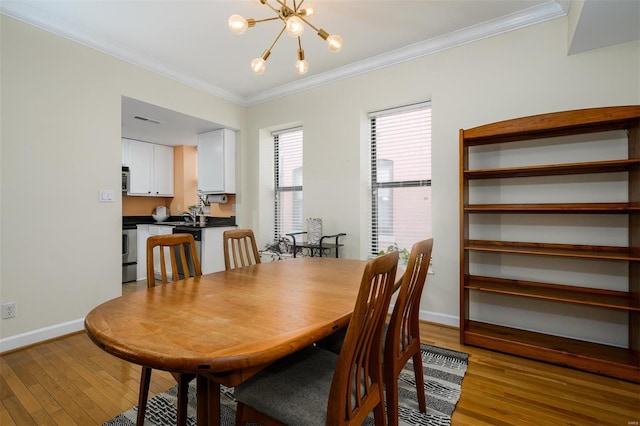 dining room with a chandelier, baseboards, light wood-style floors, and ornamental molding