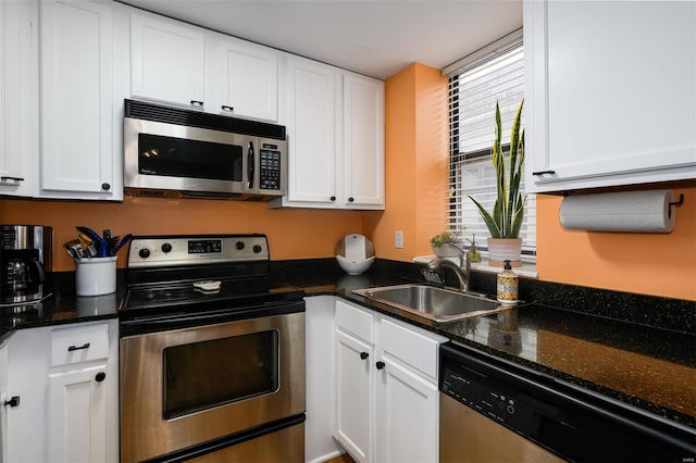 kitchen with white cabinetry, dark stone countertops, appliances with stainless steel finishes, and a sink