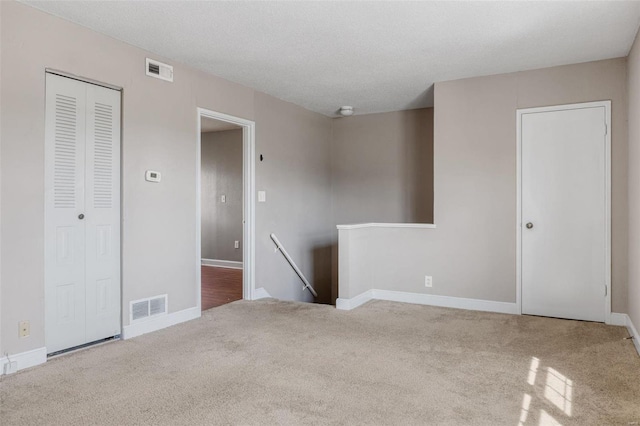 carpeted spare room with visible vents and baseboards