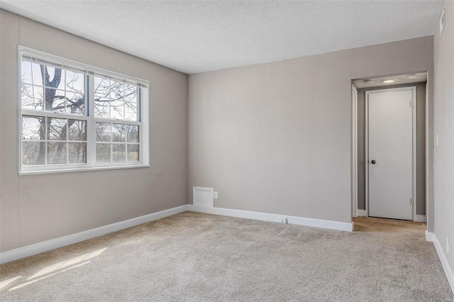 spare room featuring carpet, baseboards, and a textured ceiling