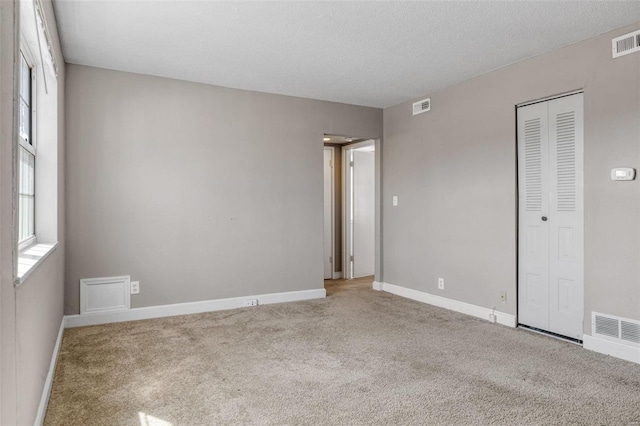 unfurnished bedroom with carpet flooring, baseboards, visible vents, and a closet