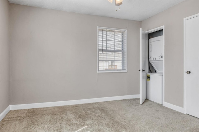 laundry area with laundry area, baseboards, stacked washer and clothes dryer, and light carpet