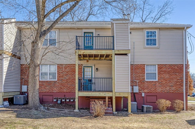 rear view of house with brick siding, central AC, and a balcony