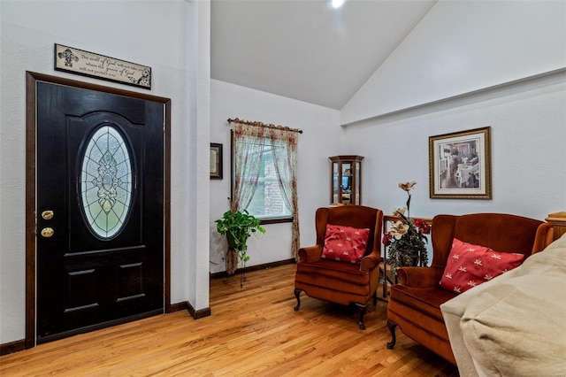 entrance foyer with a healthy amount of sunlight, light wood-type flooring, baseboards, and vaulted ceiling