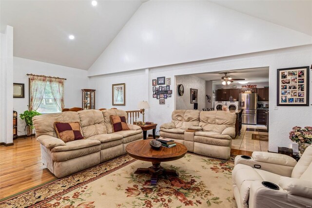 living room with washer and clothes dryer, high vaulted ceiling, and light wood-style floors