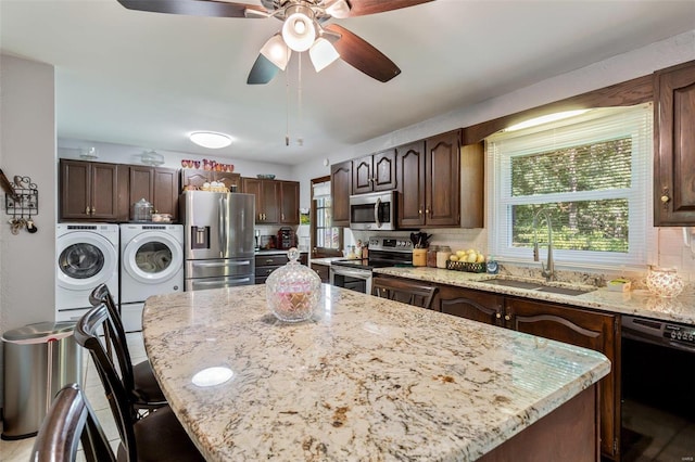 kitchen with a sink, tasteful backsplash, a kitchen island, washing machine and dryer, and stainless steel appliances