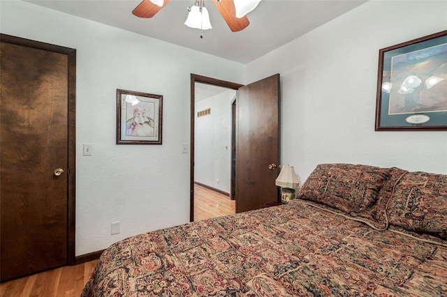 bedroom featuring visible vents, baseboards, ceiling fan, and wood finished floors