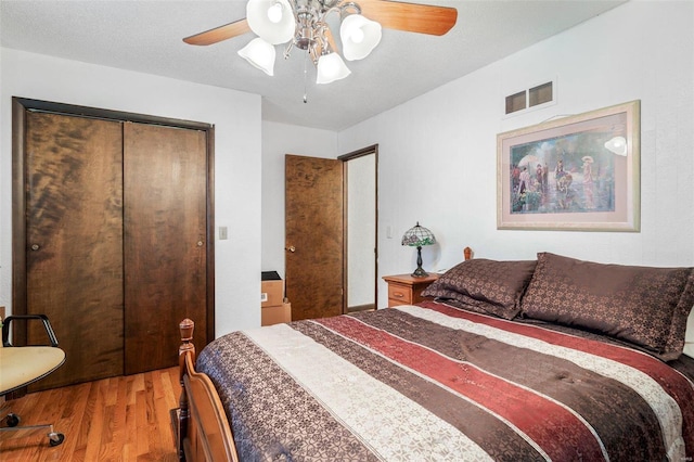 bedroom featuring visible vents, a closet, wood finished floors, and a ceiling fan