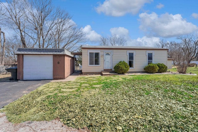 view of front of home featuring an outbuilding, driveway, a front lawn, and a garage