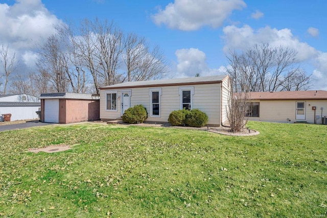 view of front facade with an outdoor structure, a front lawn, a garage, and aphalt driveway