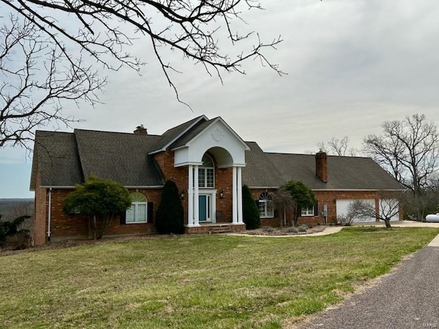 view of front facade with brick siding, a front lawn, and a chimney