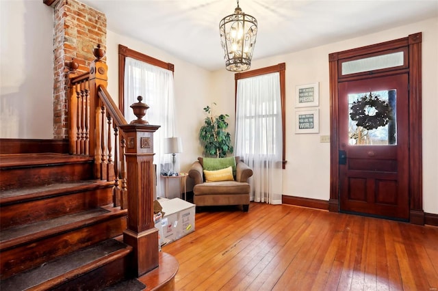 foyer with stairway, baseboards, an inviting chandelier, and hardwood / wood-style floors