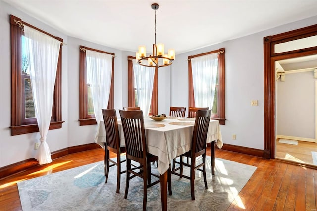 dining room with baseboards, an inviting chandelier, and hardwood / wood-style floors