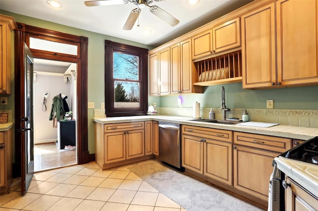 kitchen with a ceiling fan, a sink, stainless steel dishwasher, gas range oven, and light tile patterned floors