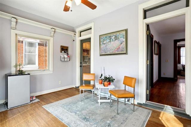 sitting room featuring wood finished floors, baseboards, and ceiling fan