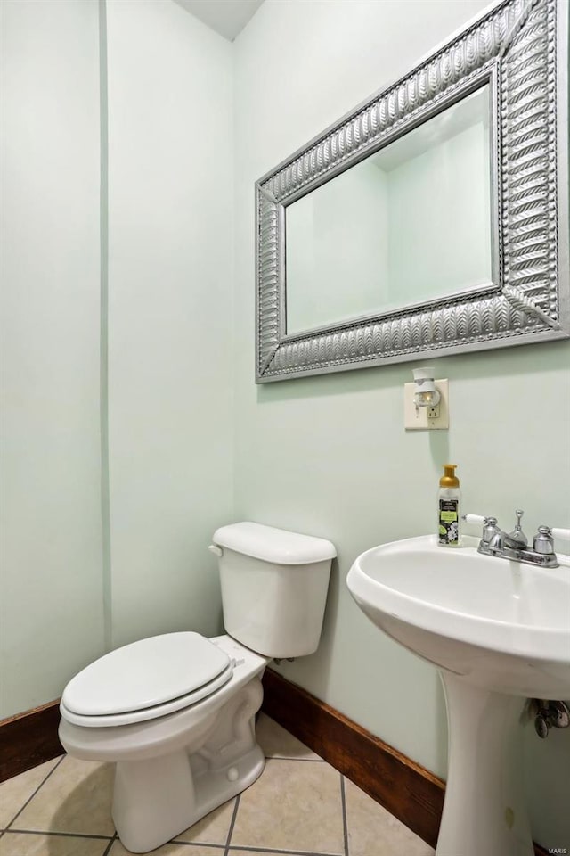 half bathroom featuring tile patterned flooring, toilet, and baseboards