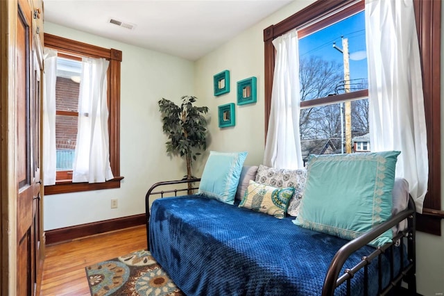 bedroom with visible vents, baseboards, and wood finished floors