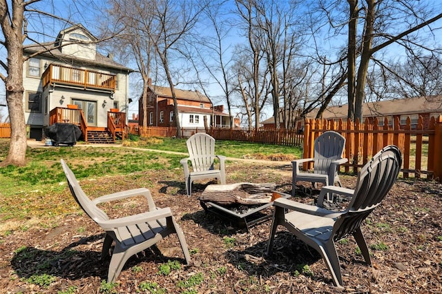 view of yard featuring a deck, a balcony, fence, and an outdoor fire pit