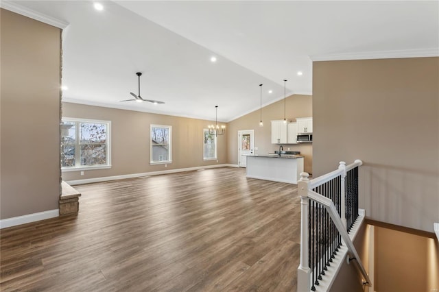 living area with baseboards, ornamental molding, dark wood-style flooring, and vaulted ceiling